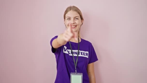 Młoda Blondynka Wolontariuszka Wskazując Palcem Kamerę Odizolowanym Różowym Tle — Wideo stockowe