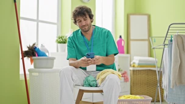 Genç Spanyol Profesyonel Temizlikçi Çamaşır Odasında Rahatlarken Akıllı Telefon Kullanıyor — Stok video