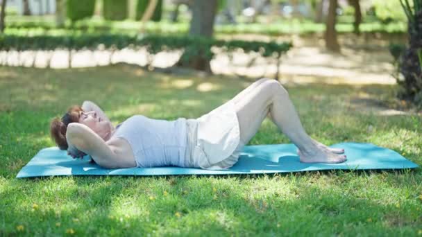 中年妇女在公园训练腹肌 — 图库视频影像