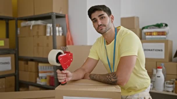 Jonge Spaanse Man Glimlacht Vol Zelfvertrouwen Leunend Donaties Kartonnen Doos — Stockvideo