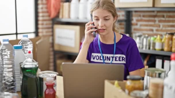 Joven Mujer Rubia Voluntaria Hablando Teléfono Inteligente Utilizando Ordenador Portátil — Vídeo de stock