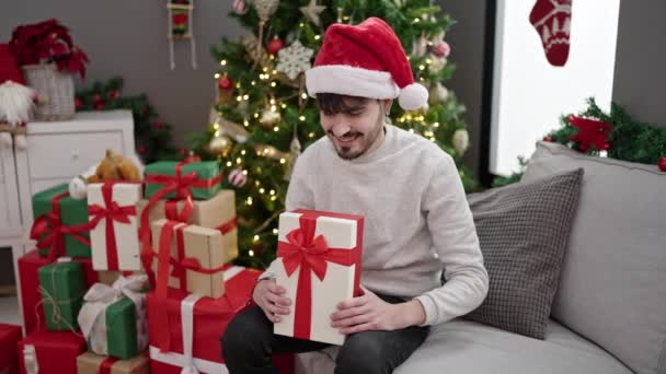 Νεαρός Ισπανός Άνδρας Χαμογελά Σίγουρος Κρατώντας Χριστουγεννιάτικο Δώρο Στο Σπίτι — Αρχείο Βίντεο
