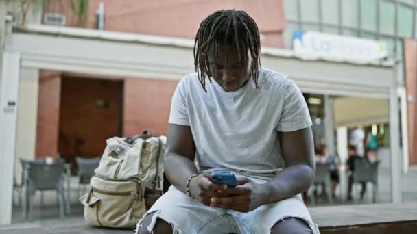 Uomo Afroamericano Che Utilizza Smartphone Seduto Sulla Panchina Sulla Terrazza — Video Stock