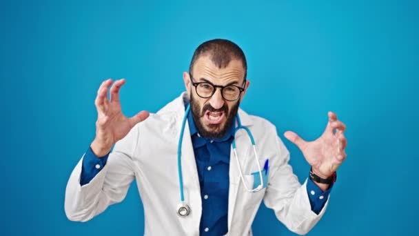 若いヒスパニックの男性医師は怒り 孤立した青い背景の上に強調しました — ストック動画
