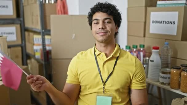 Mladý Latinský Muž Dobrovolník Drží Katarskou Vlajku Úsměvem Charitativním Centru — Stock video
