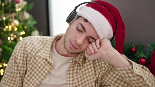 Mladý Hispánec Muž Spí Pohovce Vánočního Stromku Nosí Sluchátka Doma — Stock video