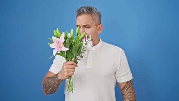 Ung Latinamerikansk Man Luktar Bukett Blommor Nyser Över Isolerad Blå — Stockvideo