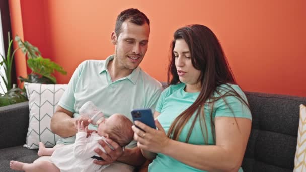 Família Três Bebê Alimentando Sentado Sofá Usando Smartphone Casa — Vídeo de Stock