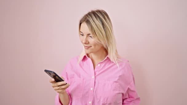 Akıllı Telefon Kullanan Genç Sarışın Kadın Pembe Arka Planda Gülümsüyor — Stok video