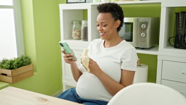 Jonge Zwangere Vrouw Die Banaan Eet Met Smartphone Eetkamer — Stockvideo