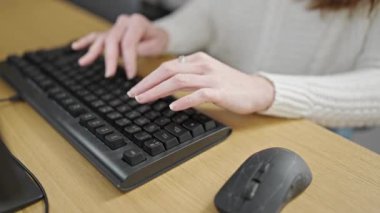 Ofiste bilgisayar klavyesi kullanan genç İspanyol kadın.