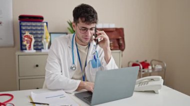Genç İspanyol doktor klinikte çalışırken dizüstü bilgisayar kullanıyor.