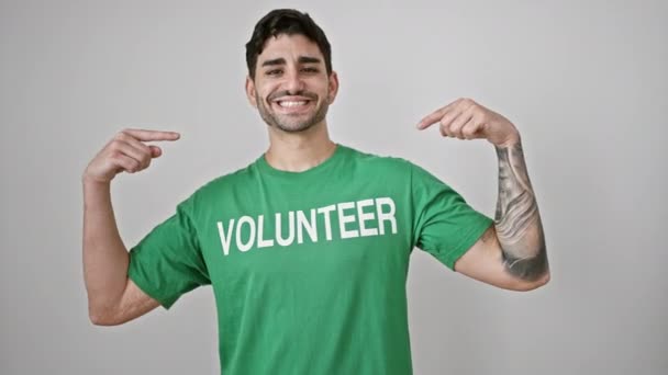 Junger Hispanischer Mann Zeigt Auf Freiwillige Uniform Und Lächelt Über — Stockvideo