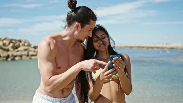 ビーチでスマートフォンを使用して一緒に立っている男女観光カップル — ストック動画