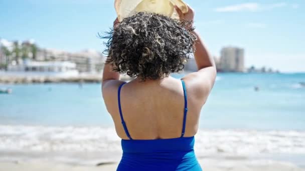 年轻美丽的拉丁女子游客身穿泳衣 头戴夏帽 倒立在海滩上 — 图库视频影像