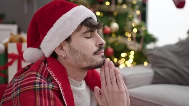 Joven Hombre Hispano Rezando Sentado Junto Árbol Navidad Casa — Vídeo de stock