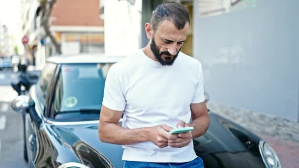 Young Hispanic Man Using Smartphone Leaning Car Street — Vídeo de stock