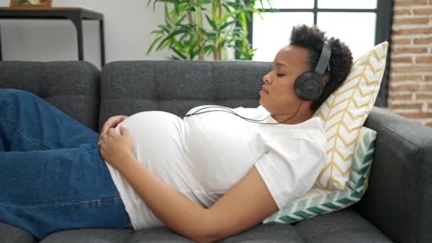 Молодая Беременная Женщина Слушает Музыку Спящую Дома Диване — стоковое видео