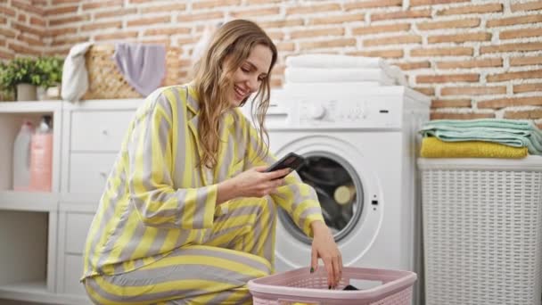 Mujer Rubia Joven Lavando Ropa Usando Smartphone Sonriendo Sala Lavandería — Vídeo de stock