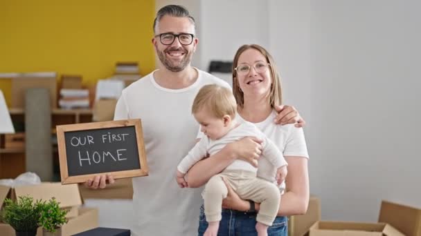 赤ん坊の家族が一緒に笑顔で新しい家でテキストを保持する — ストック動画