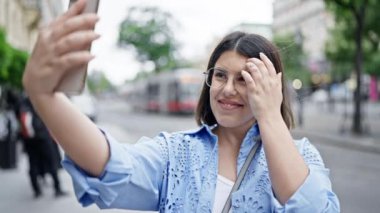 Genç ve güzel İspanyol kadın Viyana sokaklarında akıllı telefonuyla selfie çekiyor.