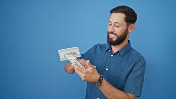 Νεαρός Ισπανός Χαμογελά Σίγουρος Ρίχνοντας Δολάρια Πάνω Απομονωμένο Μπλε Φόντο — Αρχείο Βίντεο