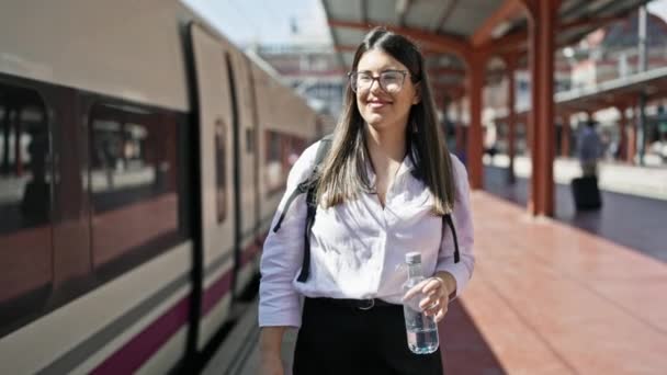 年轻美丽的惊慌失措的女人提着一瓶水沿着铁路走下火车站 — 图库视频影像