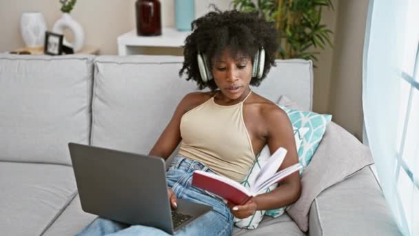 Mujer Afroamericana Leyendo Libro Usando Laptop Auriculares Casa — Vídeos de Stock