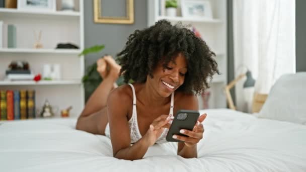 非洲裔美国女人用智能手机躺在床上 在卧室里看起来很性感 — 图库视频影像