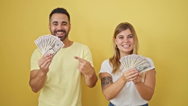 Mężczyzna Kobieta Para Uśmiecha Się Pewnie Wskazując Dolary Odizolowanym Żółtym — Wideo stockowe