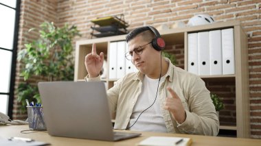 Genç İspanyol iş adamı ofiste dizüstü bilgisayar kullanarak dans ediyor.