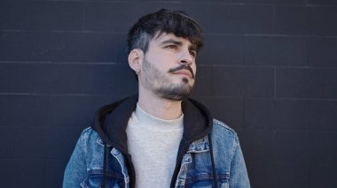 Soyutlanmış siyah arka planda ciddi bir ifadeyle duran İspanyol genç adam.