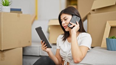 Genç beyaz kadın dokunmatik ped kullanıyor. Yeni evinde akıllı telefondan konuşuyor.