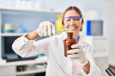Genç İspanyol bilim kadını laboratuvarda şişenin üzerine sıvı döküyor.