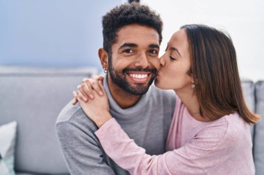 Erkek ve kadın çift evdeki kanepede oturup birbirlerine sarılıyorlar.