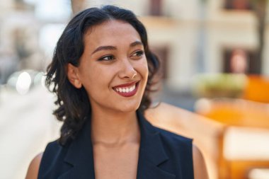 Young beautiful hispanic woman smiling confident looking to the side at street