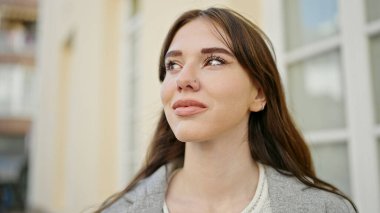 Yüzünde ciddi bir ifade olan genç İspanyol kadın caddeye bakıyor.