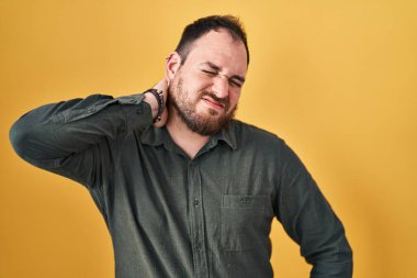 Ayrıca sarı arka planda duran, boynu ağrıyan, eli boynuna dokunan, kasları ağrıyan İspanyol bir adam. 