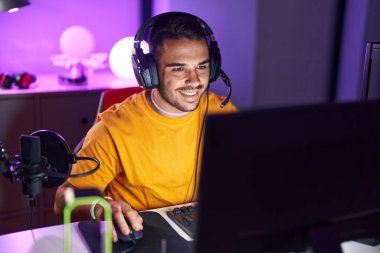 Oyun odasında bilgisayar kullanarak video oyunu oynayan İspanyol asıllı genç adam.