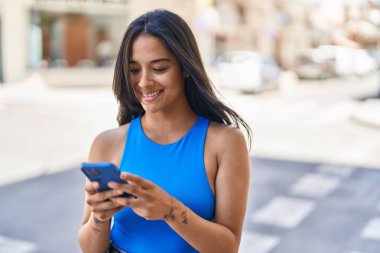 Sokakta akıllı telefon kullanan, kendine güvenen genç İspanyol kadın.