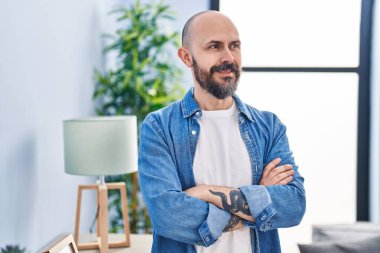 Young bald man smiling confident standing with arms crossed gesture at home
