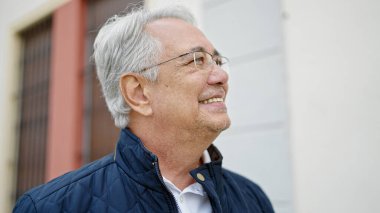 Orta yaşlı, gri saçlı, kendine güveni olan bir adam.