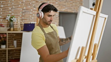 Genç İspanyol ressam resim stüdyosunda müzik dinliyor.