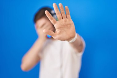 Sakallı İspanyol adam, kulaklık takıp, kulaklık takıyor, gözleri elleriyle kapatıyor ve jesti durduruyor, üzgün ve korku ifadesi takınıyor. utangaç ve olumsuz kavram. 