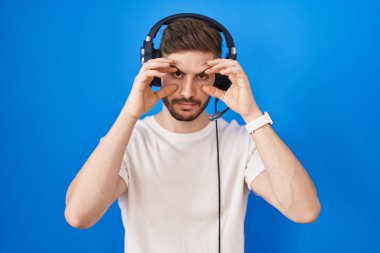 Sakallı İspanyol adam kulaklık takmış müzik dinliyor parmaklarıyla gözlerini açmaya çalışıyor, uykulu ve yorgun sabah yorgunluğu çekiyor. 