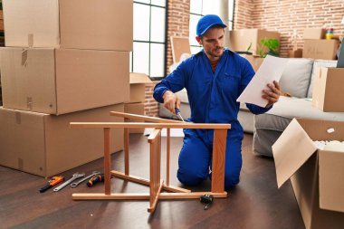 Genç İspanyol teknisyen yeni evindeki sandalyeyi tamir ediyor.