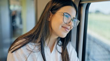 Genç, güzel İspanyol kadın mutlu bir şekilde gülümsüyor. Tren vagonunun içinden bakıyor.