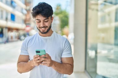 Sokakta akıllı telefon kullanan, kendine güvenen genç bir İspanyol.