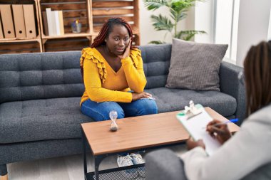 African american women psychologist and patient having mental therapy sitting on sofa at psychology clinic