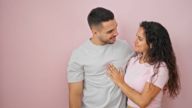 Erkek ve kadın çift gülümsüyor, kendilerine güveniyorlar, pembe arka planda sarılıyorlar.